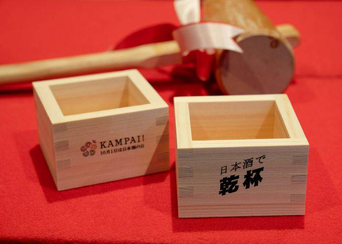 Two traditional masu sake cups, shaped as a square and made from wood.